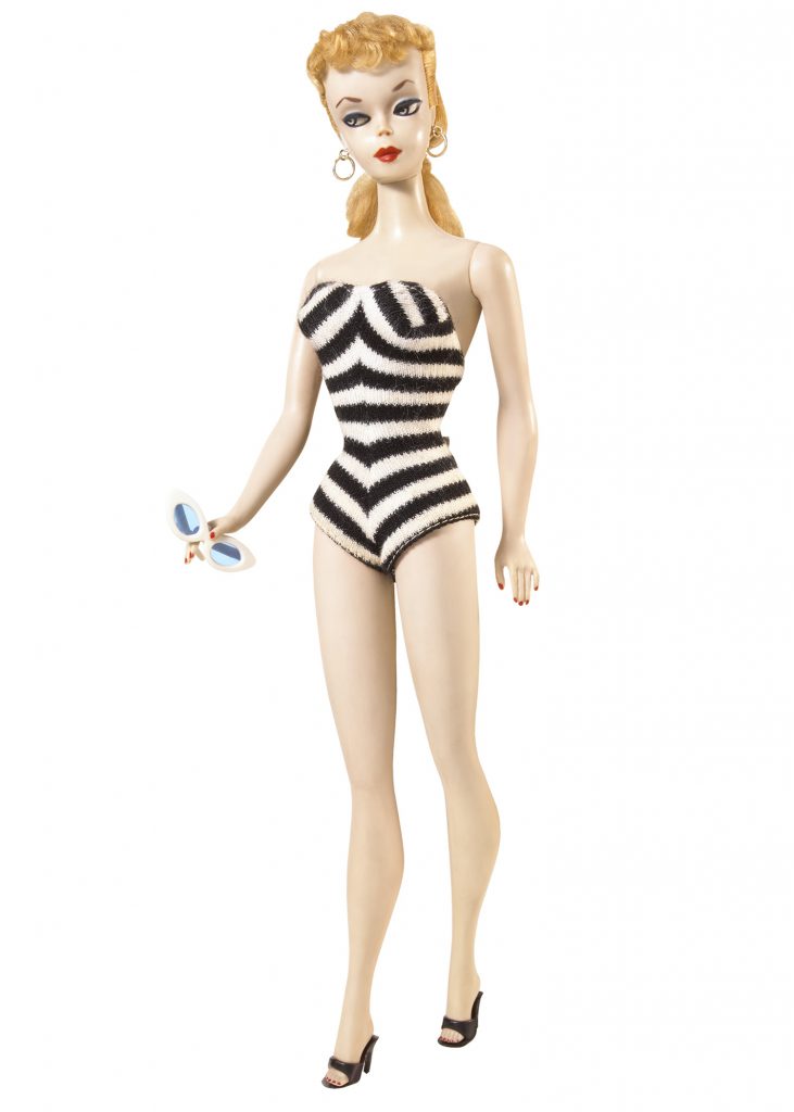 The original 1959 Barbie in a black-and-white striped suit, with pale skin and inflexible knees and elbows